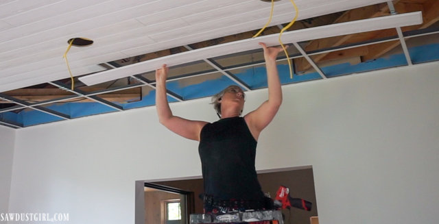 Installing wood planks on drop ceiling grid.