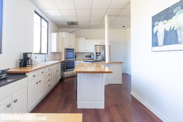 Updating a kitchen by painting dark brown cabinets - white!