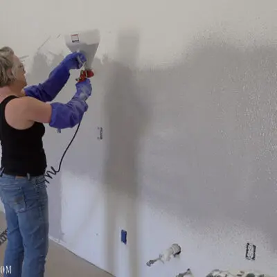 person spraying concrete on wall