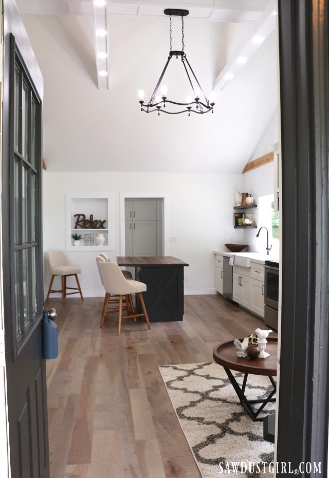 Open-concept kitchen and dining area with vaulted ceiling, wood beams, and black island in Calderwood Cottage